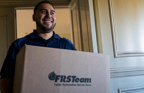 Frs Team Member smiling and holding a cardboard box
